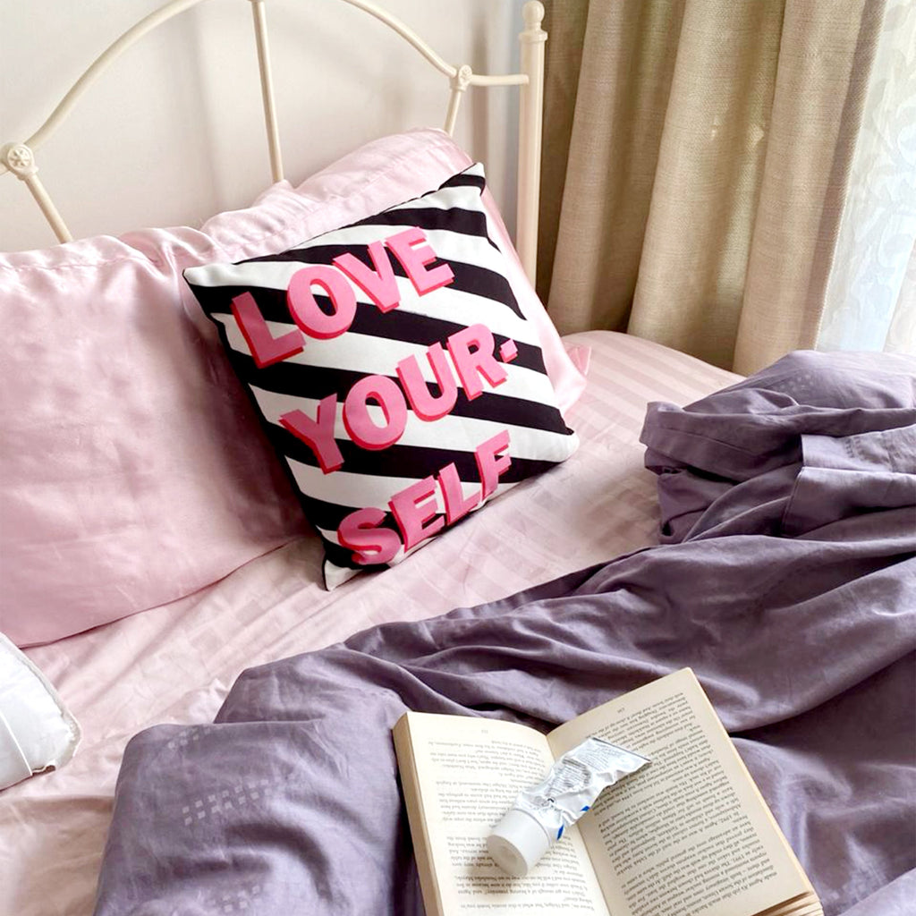 Love Yourself Cushion Cover on a bed